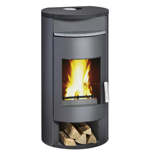 Das Bild zeigt den Atlas Typ.10181 Kaminofen von Wamsler mit brennendem Feuer im Sichtfenster, der Energieeffizienzklasse A+, und einer Ablage für Brennholz am unteren Ende des Ofens. Der Ofen ist in einem dunkelgrauen Ton gehalten und hat eine runde, aufrechte Bauform. Die Oberseite des Ofens scheint mit einer Art Steinmaterial verkleidet zu sein, das als Wärmespeicher dient.